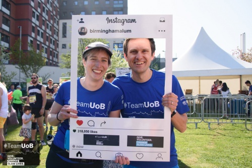 Man and woman pose with large picture frame