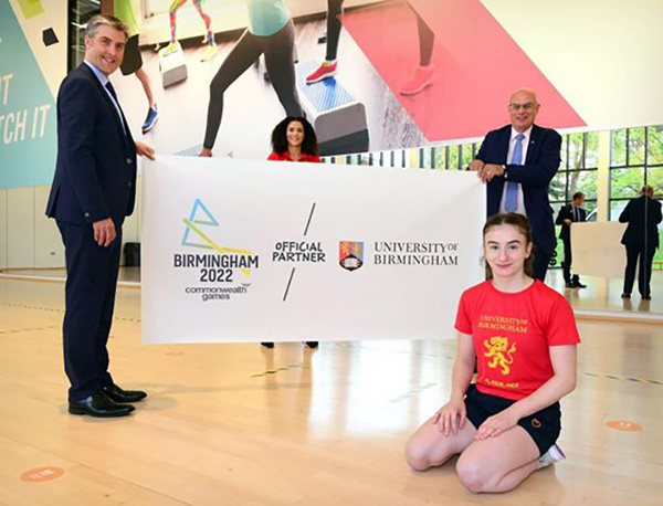 Two men holding a banner, with female athletes in foreground and background