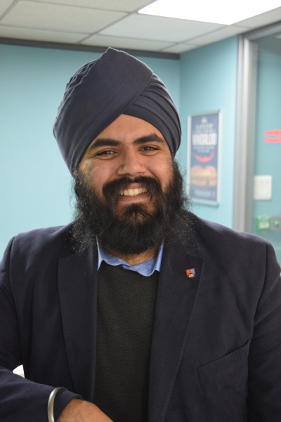 Dr Amrid Chandan looking at camera in blazer and UoB pin badge