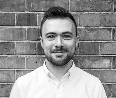 James in front of brick wall in black and white