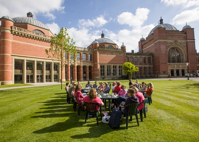 Alumni sat at tables in front of the Aston Webb Building in the sun