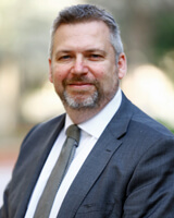 Glyn Watson wearing a grey suit and tie