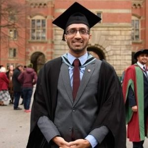 Judah Chandra in graduation cap and gown outside the Great Hall