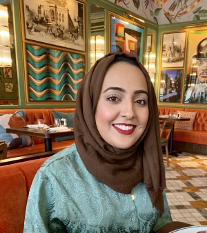 Madiha Majid at a restaurant with artwork filling the walls behind her