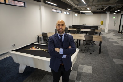 PJ Ellis standing in an office in a suit with arms folded