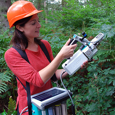 Woman holding scientific equipment in forest