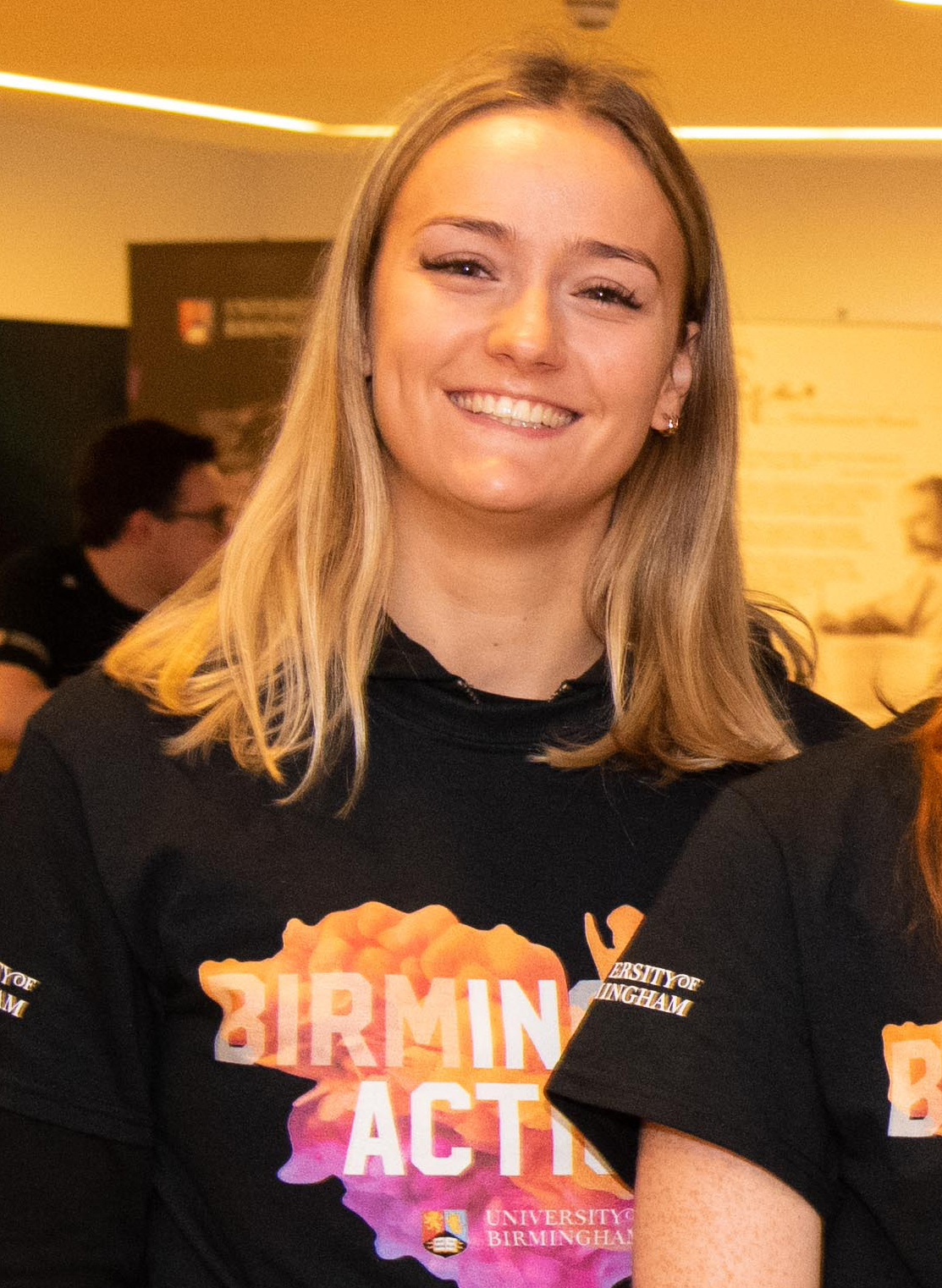 Female student wearing black, orange and purple t-shirt that says 'Birmingham In Action'