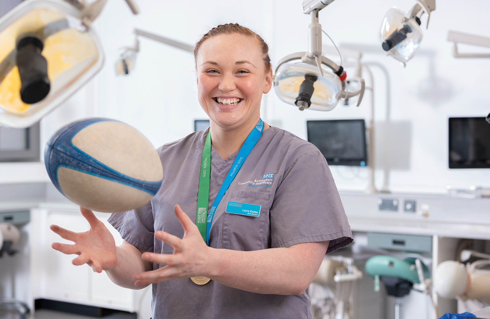 Woman catching a rugby ball while wearing dentist clothing inside a dental practice