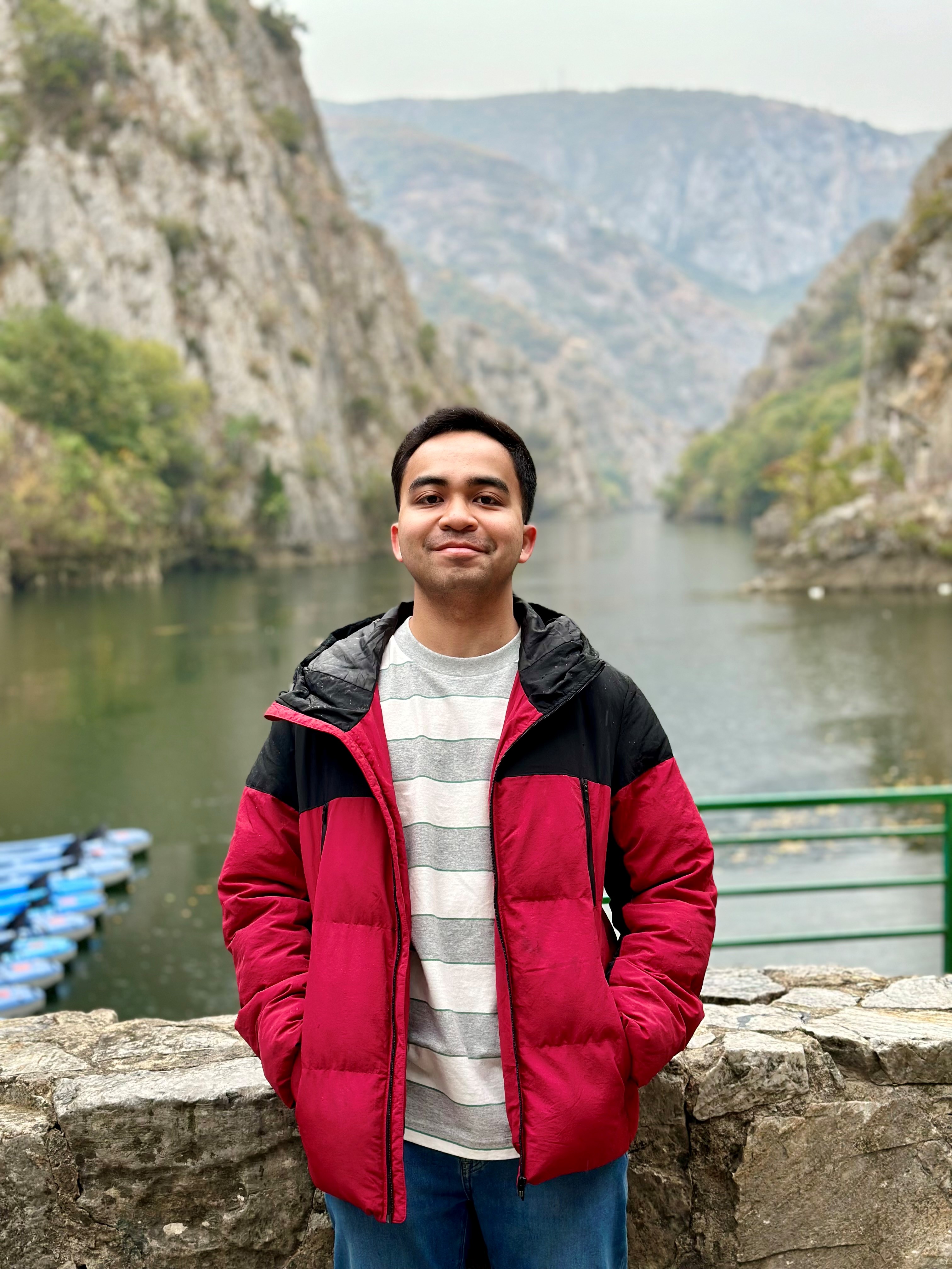 Arief smiling at the camera with mountains in the background