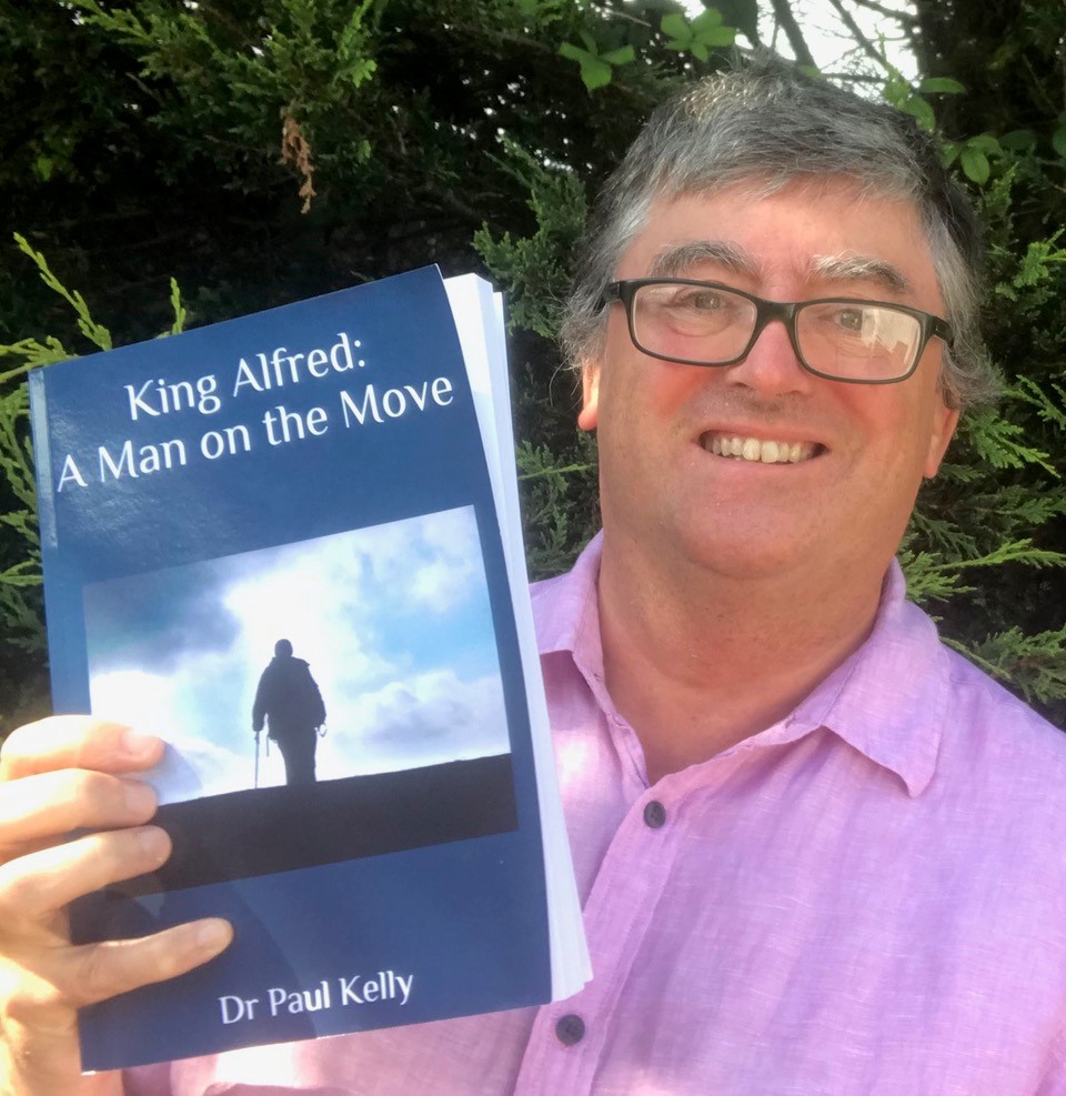 Dr Paul Kelly holding the book he wrote, King Alfred: A Man on the Move