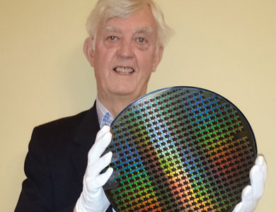 Man holding a disc of silicon chips, wearing white gloves