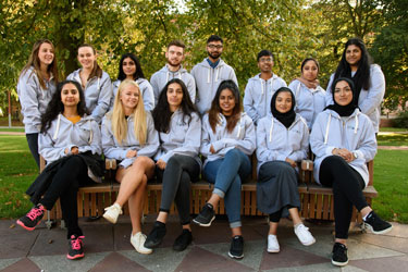 14 Lloyds Scholars from a range of backgrounds, wearing matching hoodies on campus