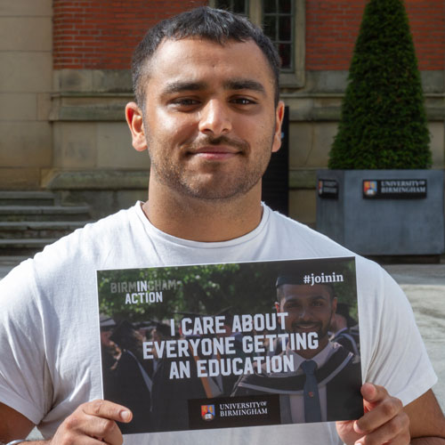 Pav standing outside the Aston Webb Building, holding a board that says I care about everyone getting an education