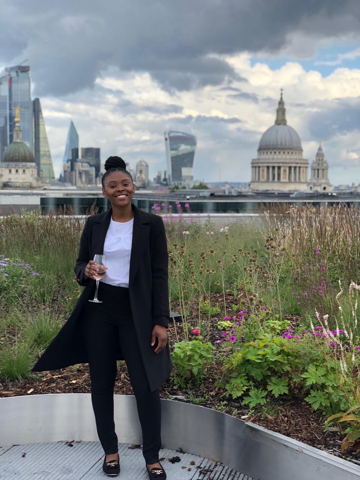 Girl with a champagne glass standing outside behind London skyline